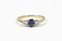 Lot 1050 - A gold step cut sapphire and diamond three stone ring