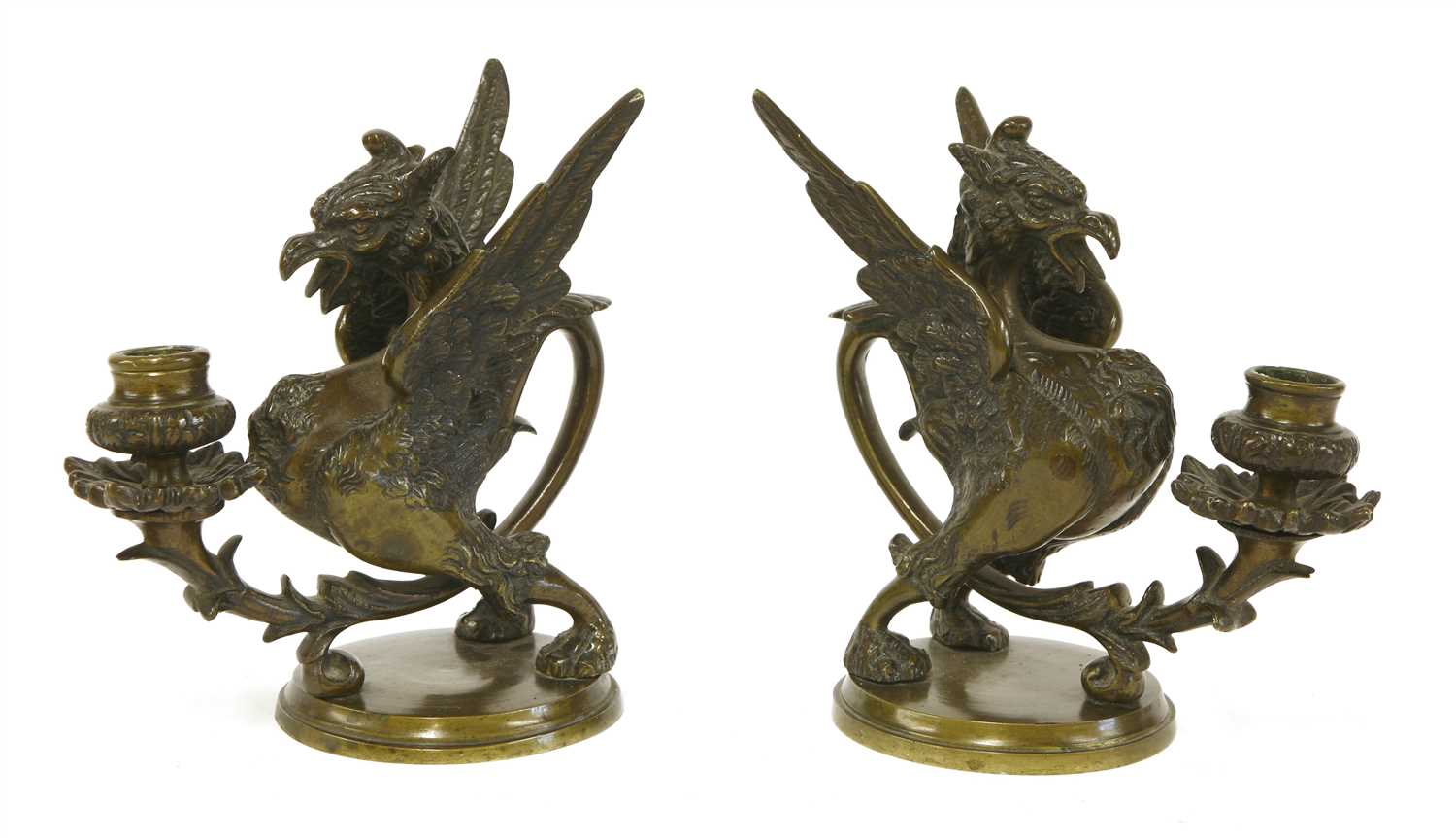 Lot 501 - A pair of dark brown patinated bronze griffin/wyvern candlesticks