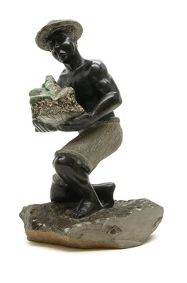 Lot 376 - A South American hardstone sculpture of an agricultural worker wearing a hat and carrying a rock