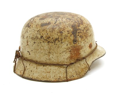 Lot 179 - A WWII German rolled edge M35 snow camouflaged combat helmet