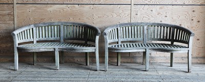 Lot 995 - A pair of Lutyens-style curved teak garden benches