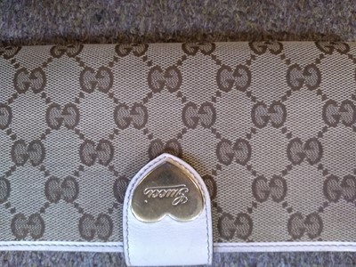 Lot 101 - A Gucci beige monogrammed canvas and cream leather heart bi-fold wallet