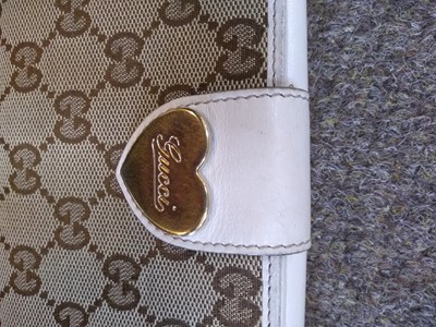 Lot 101 - A Gucci beige monogrammed canvas and cream leather heart bi-fold wallet