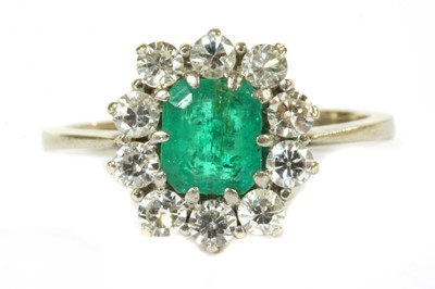 Lot 357 - A white gold emerald and diamond cluster ring