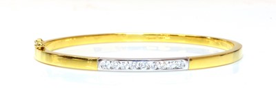 Lot 325 - An 18ct two colour gold diamond set hinged bangle
