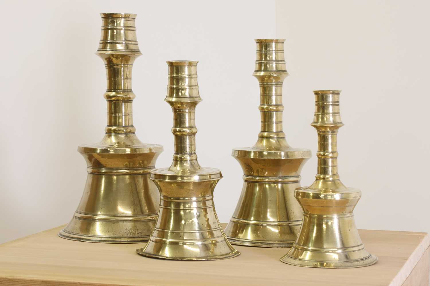 Lot 391 - A graduated set of four bell-shaped brass candlesticks