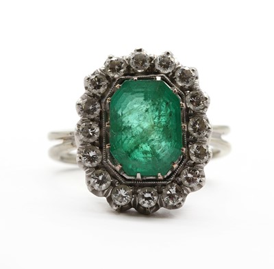 Lot 230 - A white gold emerald and diamond cluster ring
