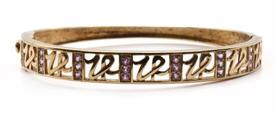 Lot 178 - A 9ct gold pink sapphire set hinged oval bangle