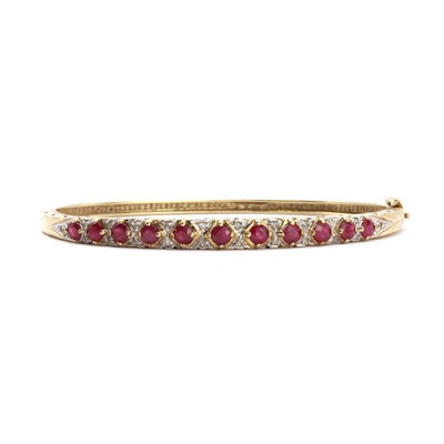 Lot 64 - A 9ct gold ruby and diamond hinged bangle