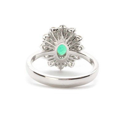 Lot 106 - A white gold emerald and diamond cluster ring