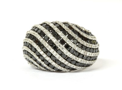 Lot 1093 - A white gold, black and white diamond bombé ring