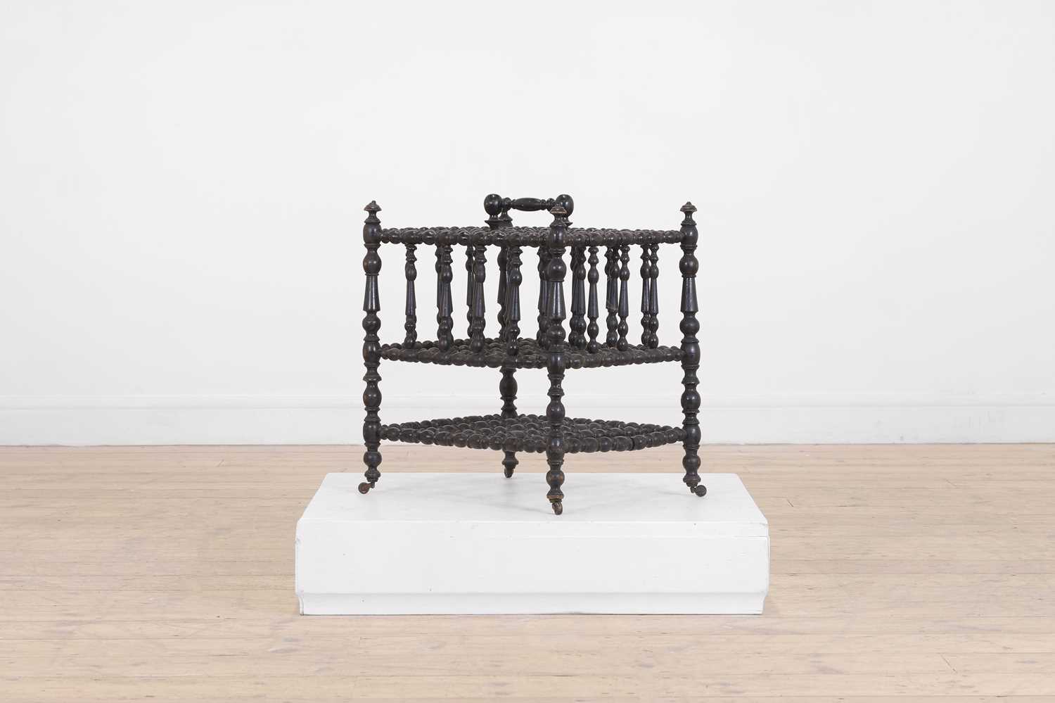 Lot 23 - An ebonised wooden magazine rack