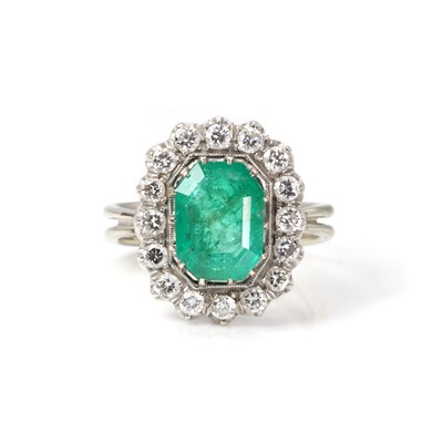 Lot 154 - A white gold emerald and diamond cluster ring