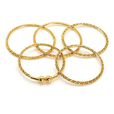 Lot 309 - A set of four gold bangles and another