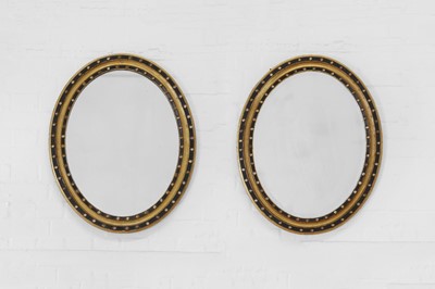 Lot 228 - A pair of George III ebonised and parcel-gilt oval mirrors