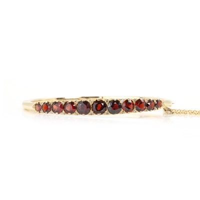 Lot 112 - A 9ct gold garnet set hinged bangle